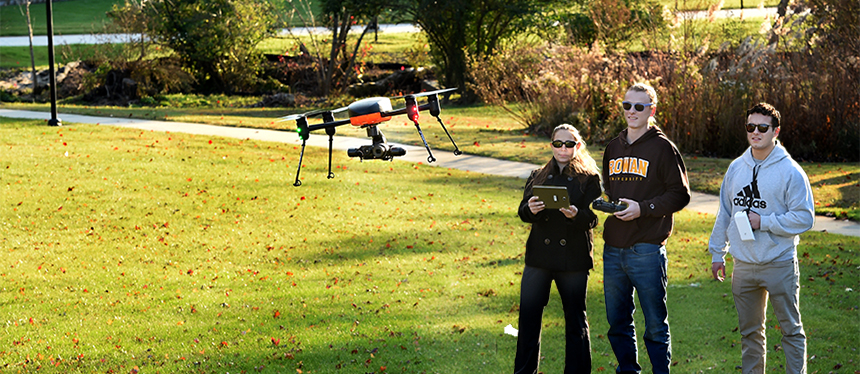 3 students flying a drone outside