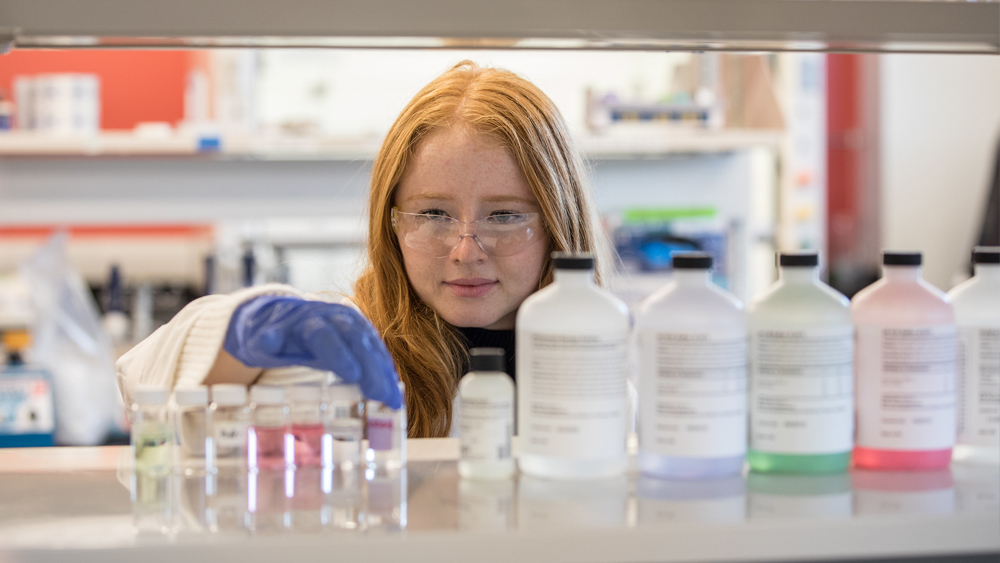 female student measuring chemicals in beaker in lab