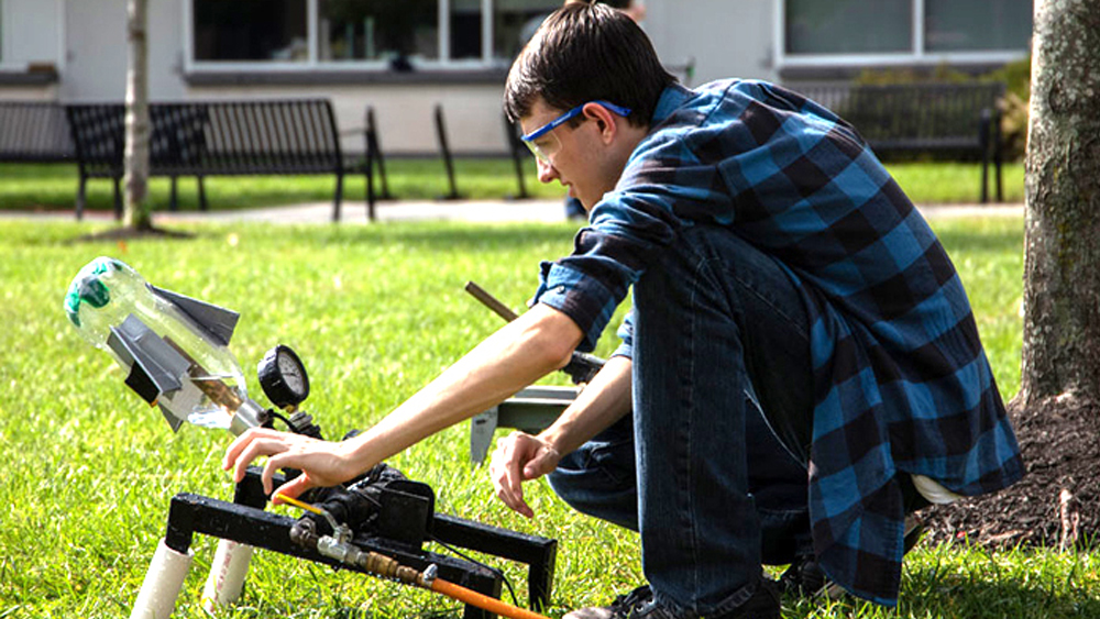 A male student adjusting a handmade water bottle launcher