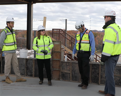 4 people in hard hats and vests outside at a construction site