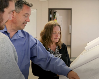 three people looking at large paper on table