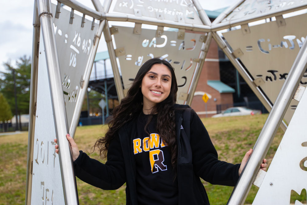 A Rowan graduate student standing inside one of the engineering statues